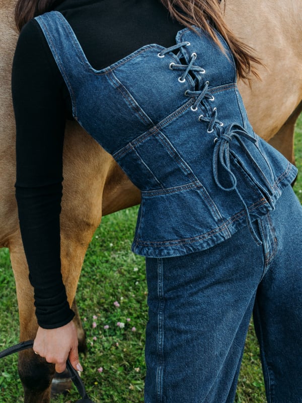 Kacey Musgraves usando espartilho jeans de lavagem média com jeans combinando