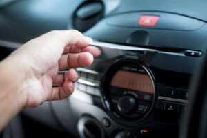 O homem inserindo o CD no CD player do carro.