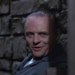 Anthony Hopkins como Hannibal Lecter sorrindo de sua cela em O Silêncio dos Inocentes.