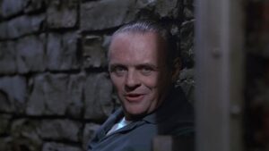 Anthony Hopkins como Hannibal Lecter sorrindo de sua cela em O Silêncio dos Inocentes.