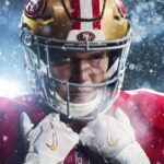 A football player holding his pads, wearing a 49ers uniform.