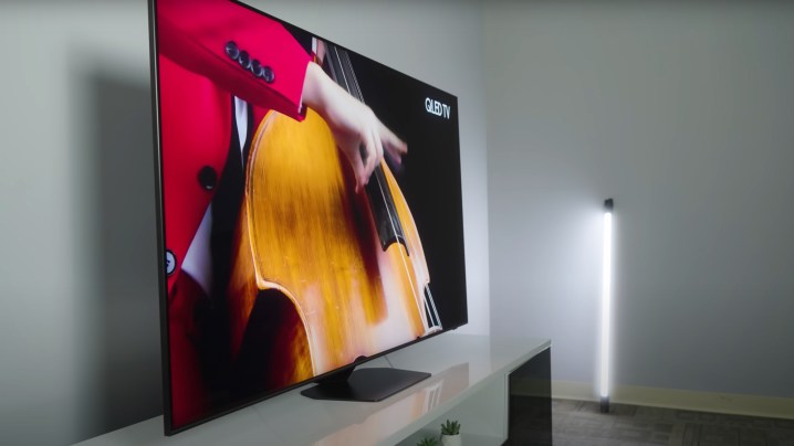 Um close de um artista com uma jaqueta vermelha tocando um contrabaixo mostrado em uma TV Samsung QN90D.