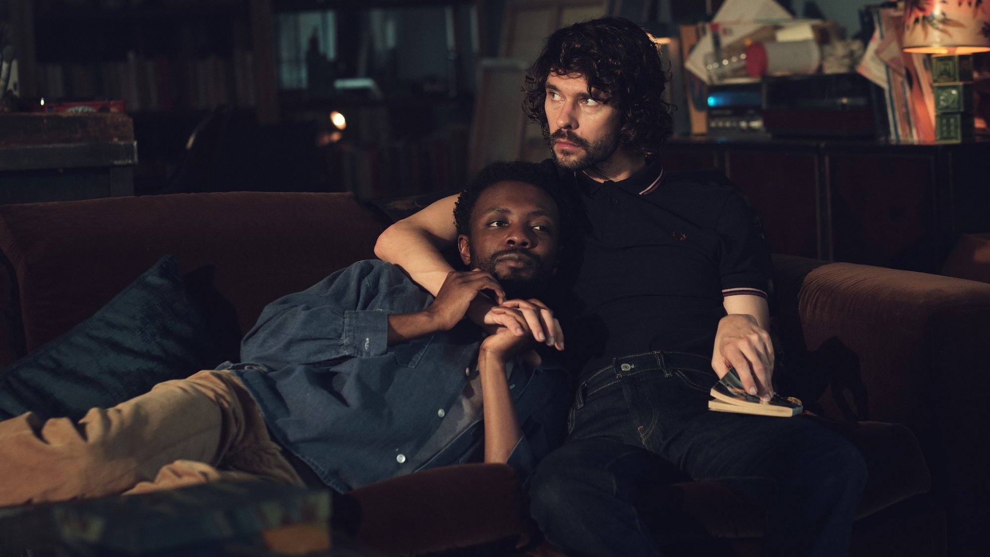 Omari Douglas e Ben Whishaw abraçados em um sofá em uma foto de 