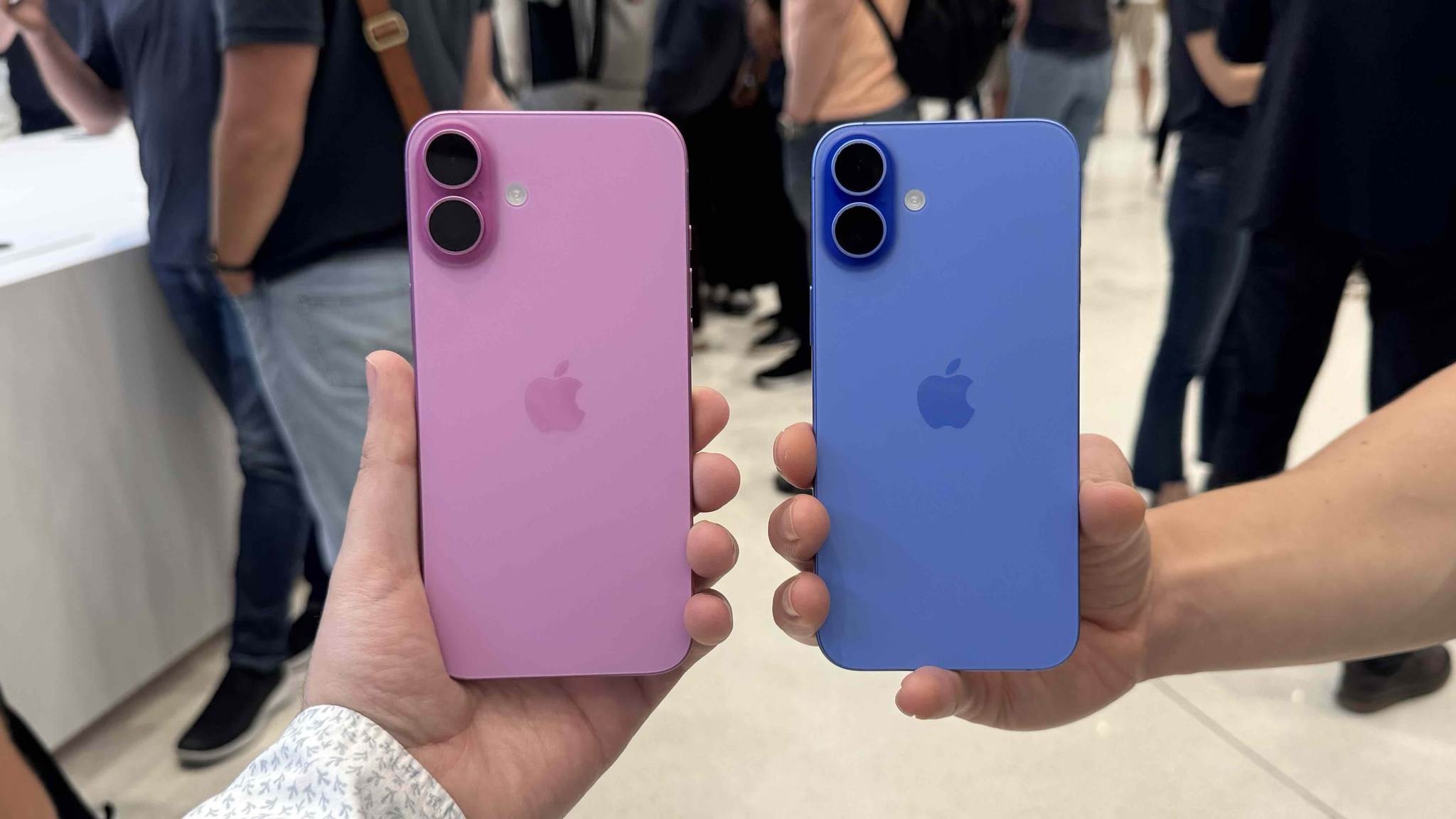 Duas unidades do iPhone 16 em rosa e ultramarino seguradas com as duas mãos.