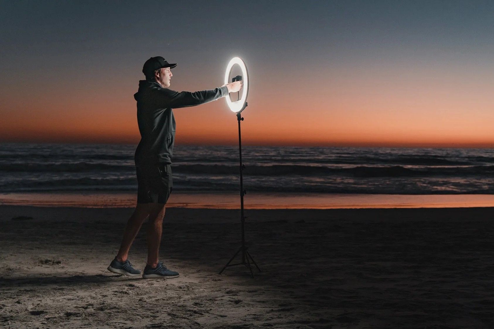 Um homem usando um anel luminoso em uma praia durante a noite.