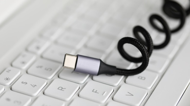 Cabo USB-C enrolado no teclado de um laptop