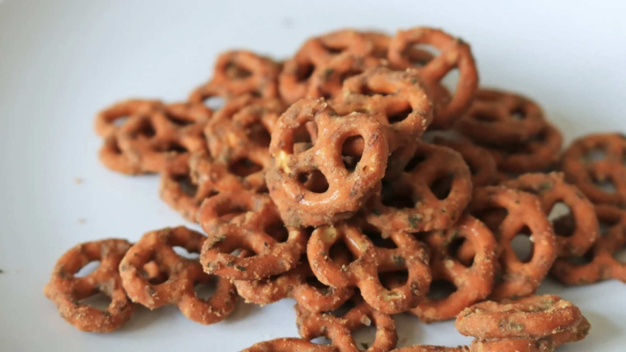 Pretzels temperados empilhados num prato branco.