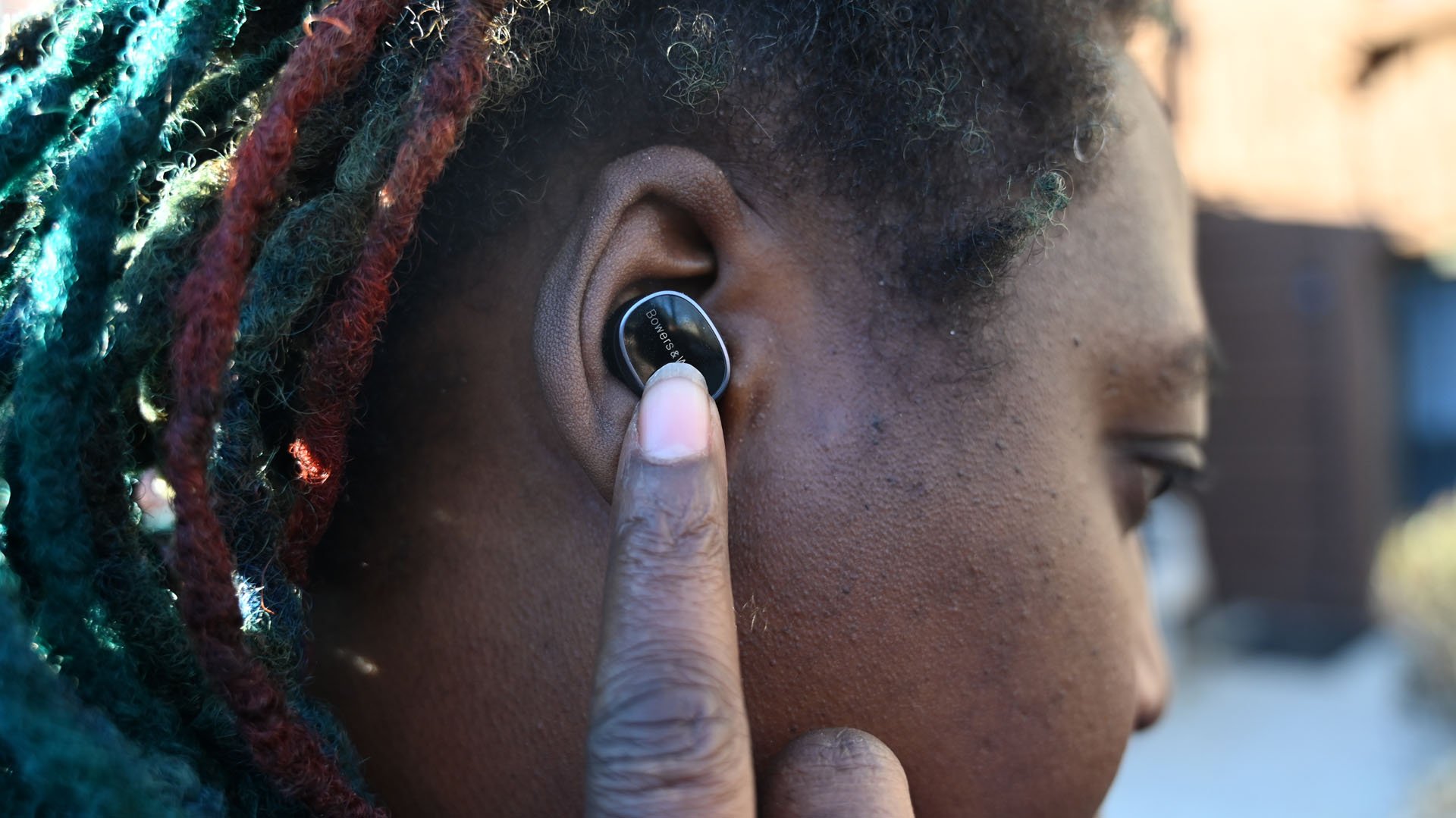 Foto de uma mulher afro-americana usando fones de ouvido Bowers & Wilkins Pi8 usando controle de toque