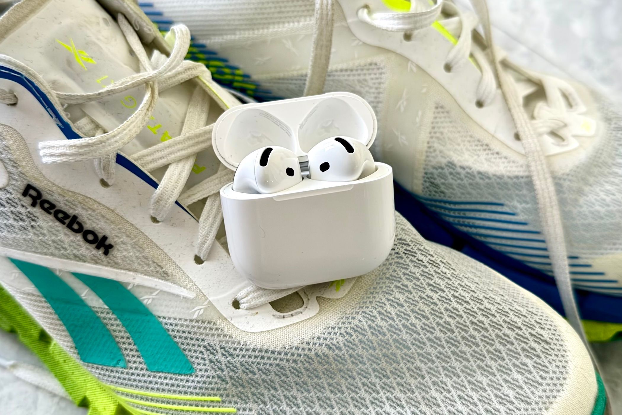 AirPods 4 sentado em um par de tênis de corrida