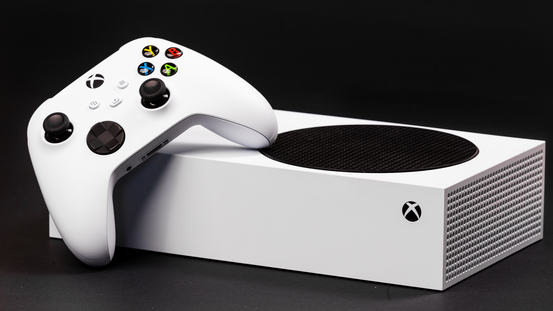 Um Xbox Series S colocado horizontalmente com um controlador Xbox Series apoiado nele. 