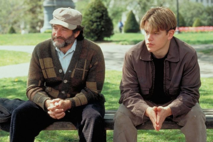 Robin Williams e Matt Damon sentam-se lado a lado em um banco.