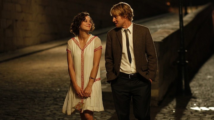 Uma mulher e um homem caminham pela rua em Paris em Midnight in Paris.