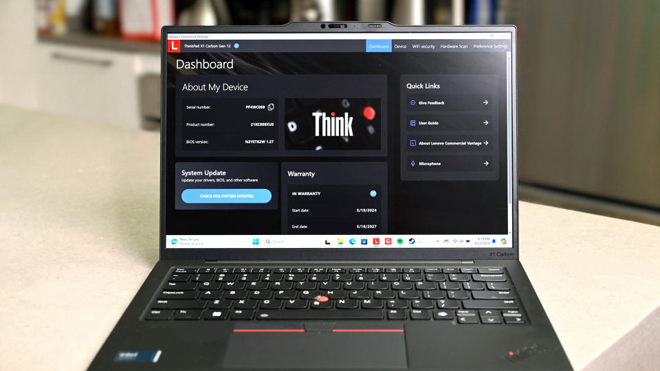 O Lenovo ThinkPad X1 Carbon (12ª geração) com tela e teclado voltados para a câmera. Em sua tela está o painel Think da Lenovo mostrando informações sobre o dispositivo, incluindo atualização do sistema e garantia.