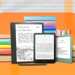 3 Kindles diferentes, lado a lado, com alguns livros atrás deles.