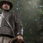 Screenshot from Indiana Jones and the Great Circle featuring a shot of Indiana Jones a white male wearing a brown leather jacket and brown leather hat standing in front of a Buddhist statue.