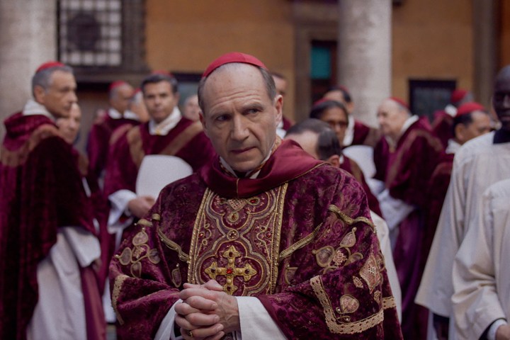 Ralph Fiennes caminha por uma multidão de cardeais católicos no Conclave.