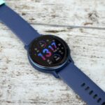 O Garmin Vivoactive 5 colocado sobre madeira pintada, voltado para cima.