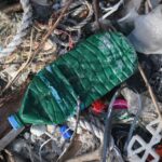 A close-up of a pile of garbage, including a plastic beverage bottle, bubble wrap, rope, and string.