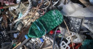 A close-up of a pile of garbage, including a plastic beverage bottle, bubble wrap, rope, and string.