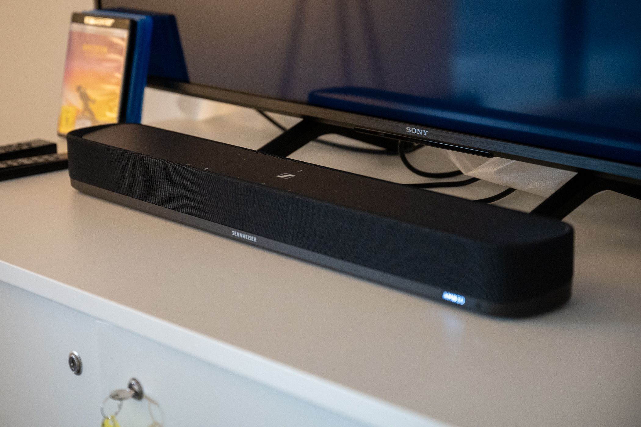 Sennheiser AMBEO Soundbar Mini sentado em frente a uma TV.