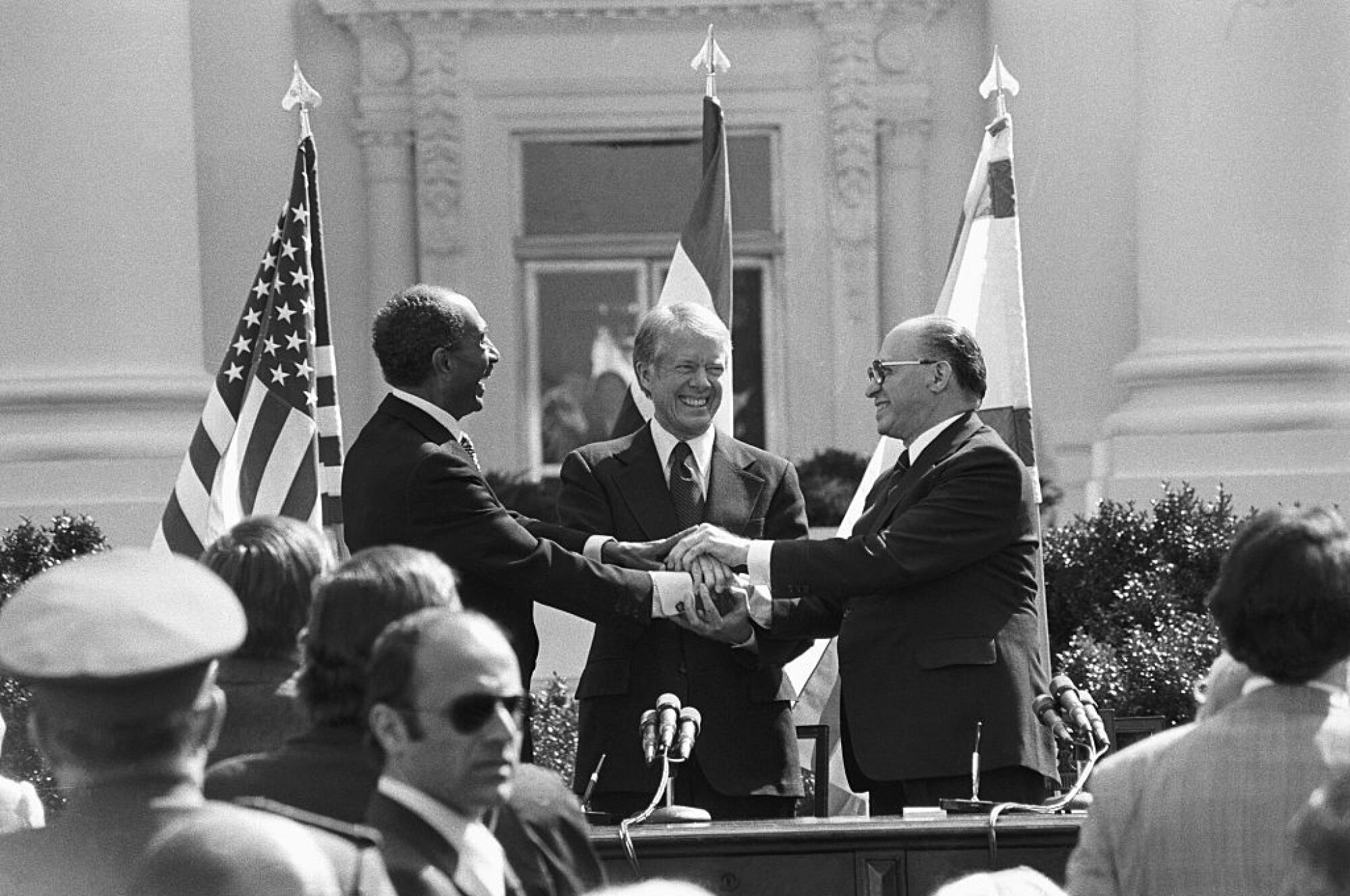 O presidente Jimmy Carter, Anwar Sadat e Menachem Begin trocam um aperto de mão triplo após assinarem os Acordos de Camp David.