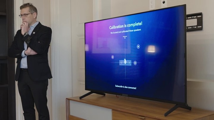 Um homem ao lado de uma TV que mostra que a calibração do Dolby Atmos FlexConnect foi concluída na CES 2024.