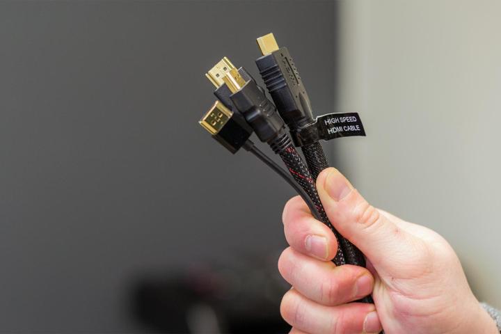 Três cabos HDMI na mão de alguém.