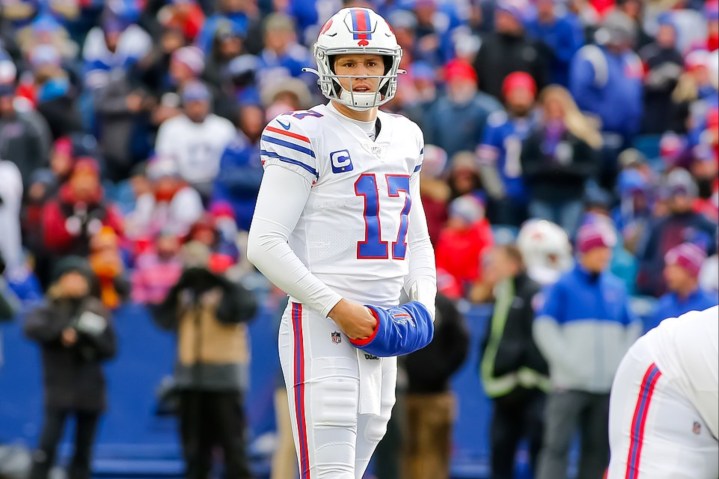 Josh Allen coloca as mãos em um aquecedor de mãos no campo.