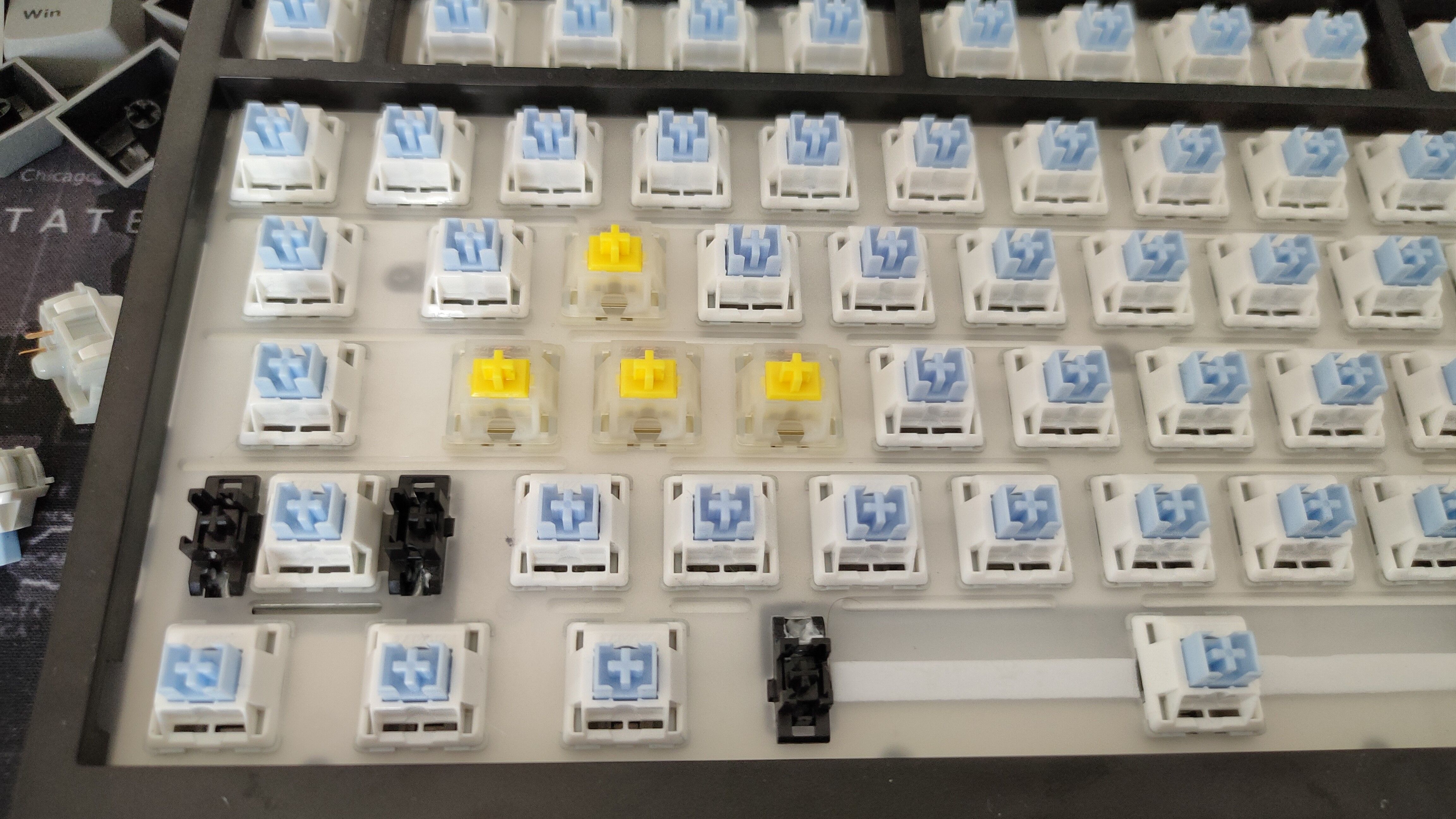 Um teclado com as teclas removidas e alguns interruptores amarelos Gateron no lugar das teclas WASD.