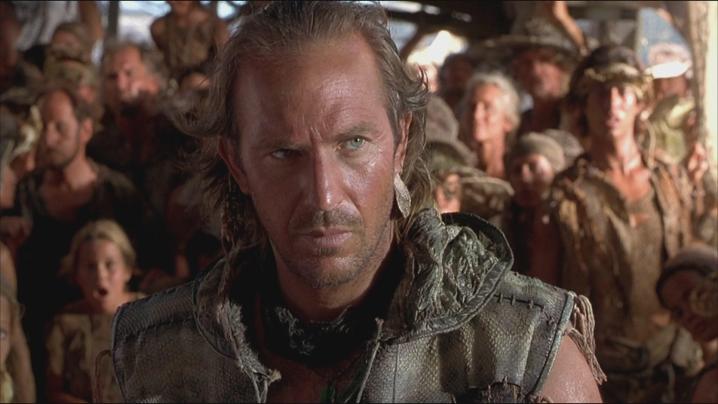 Kevin Costner está na frente de um grupo de pessoas no Waterworld.