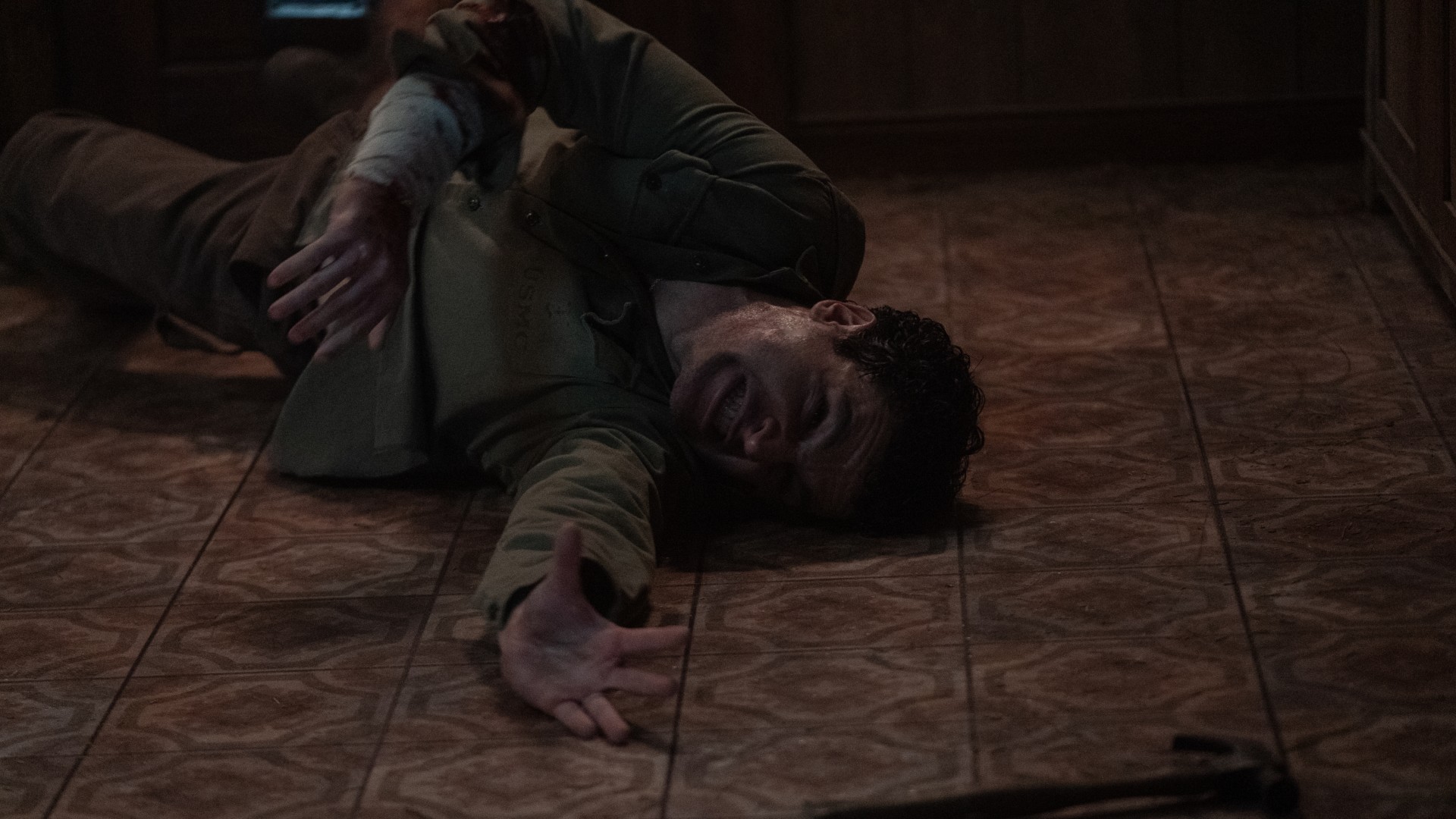 Christopher Abbott se contorce no chão e pega um martelo em uma foto do filme Wolf Man.