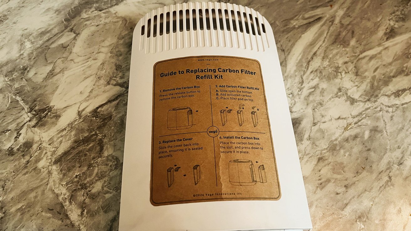 Device on marble surface with a brown sticker showing a four-step guide to replacing a carbon filter refill kit, accompanied by diagrams.