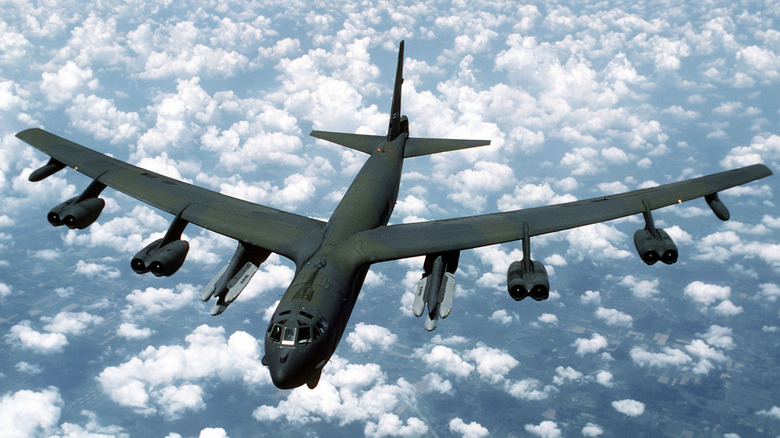 Um B-52G armado com mísseis de cruzeiro lançados do ar voando sobre nuvens quebradas