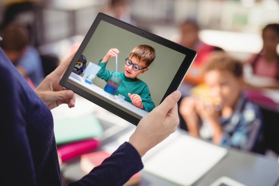 Uma mulher segurando um tablet ASUS Chromebook na mão durante uma aula.