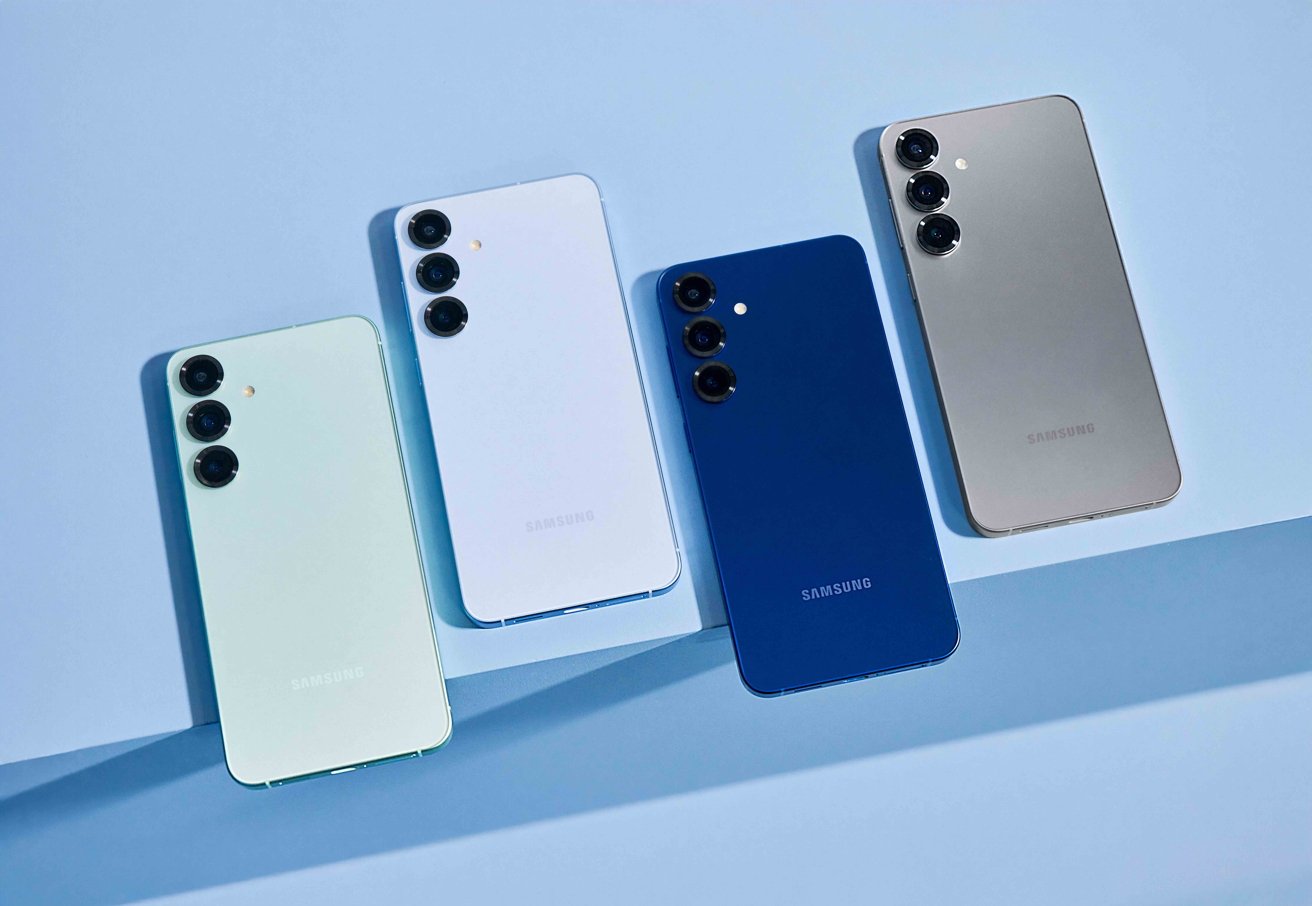 Four smartphones in various colors—  white, light blue, dark blue, and beige—  stand on a light blue surface, each with three rear cameras aligned vertically.