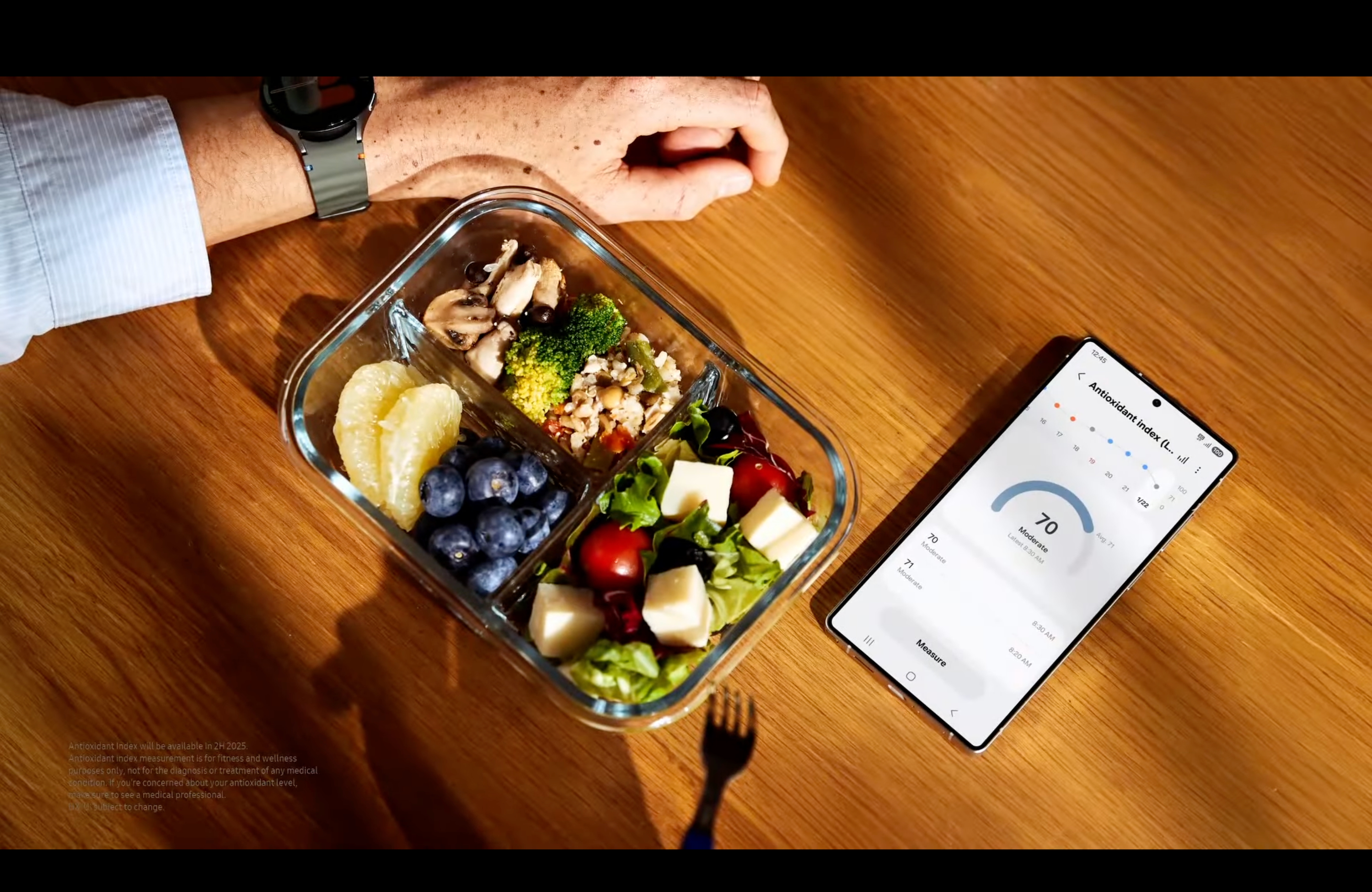 Uma foto de um telefone Samsung mostrando o aplicativo Samsung Health mostrando o índice antioxidante, ao lado de um prato de comida com aparência saudável.