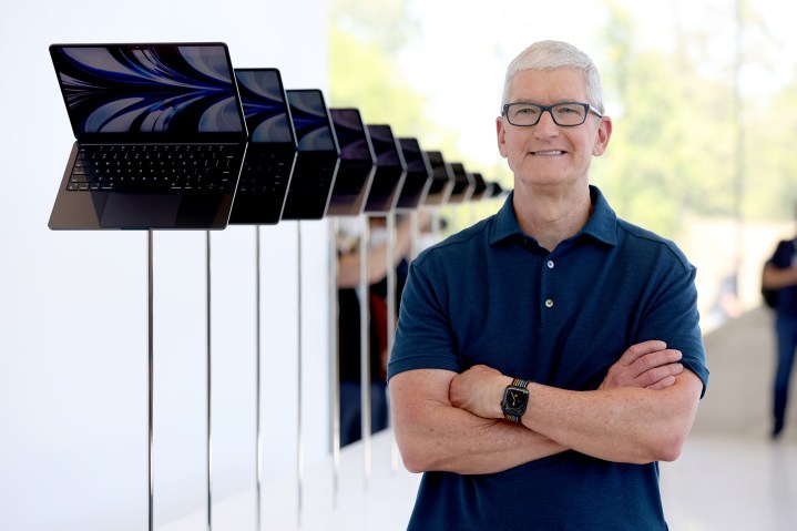 O CEO da Apple, Tim Cook, olha para a tela do novo laptop MacBook Air redesenhado durante a WWDC22