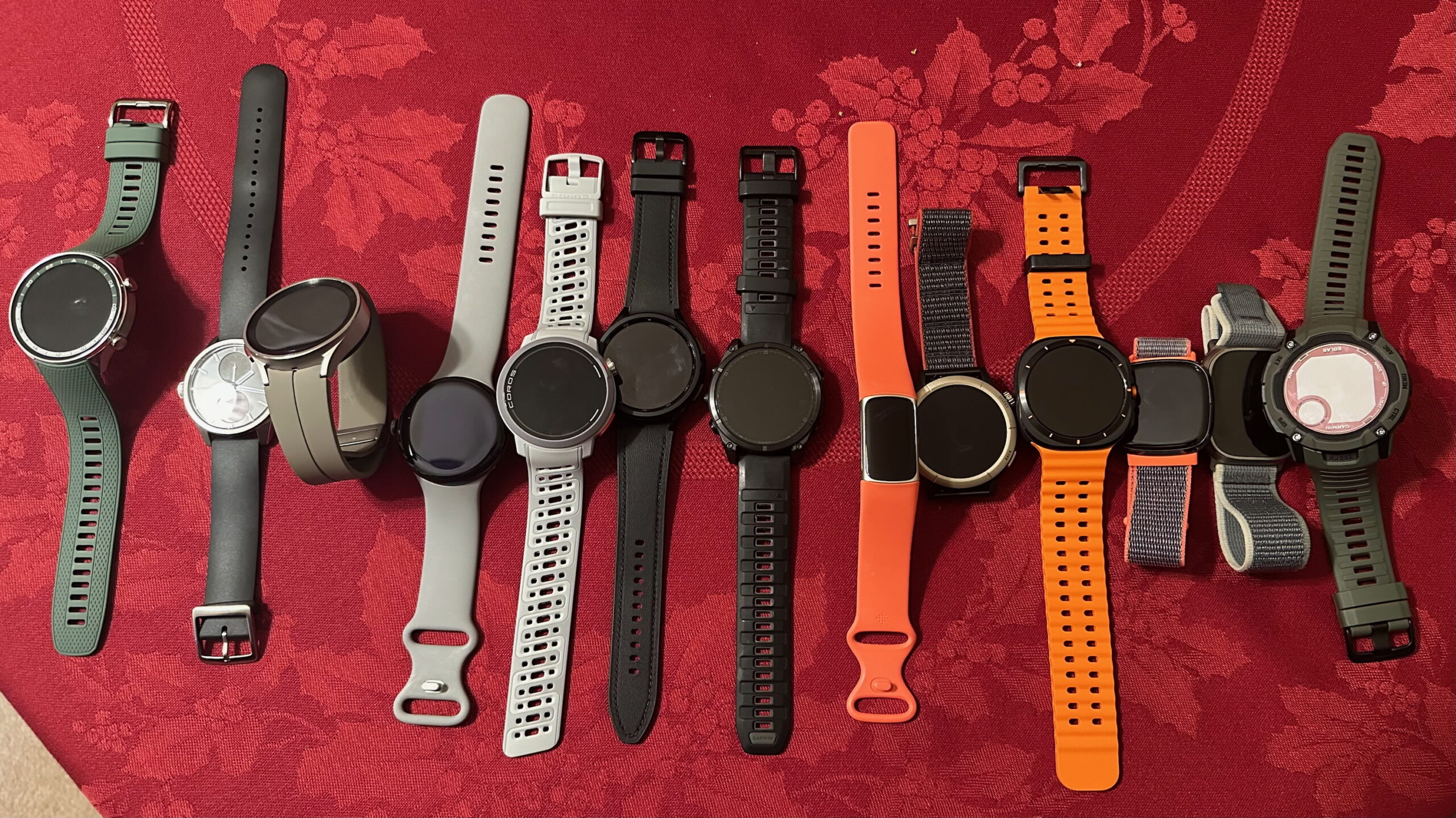 Uma visão de cima para baixo de treze smartwatches lado a lado em uma mesa. Em ordem, eles são OnePlus Watch 2R, Withings ScanWatch 2, Samsung Galaxy Watch 5 Pro, Google Pixel Watch 3, Coros Pace Pro, Samsung Galaxy Watch 6 Classic, Garmin Fenix ​​8, Fitbit Charge 6, Amazfit Cheetah Pro, Samsung Galaxy Watch Ultra, Fitbit Sense, Apple Watch Ultra 2 e Garmin Instinct 2X Solar.