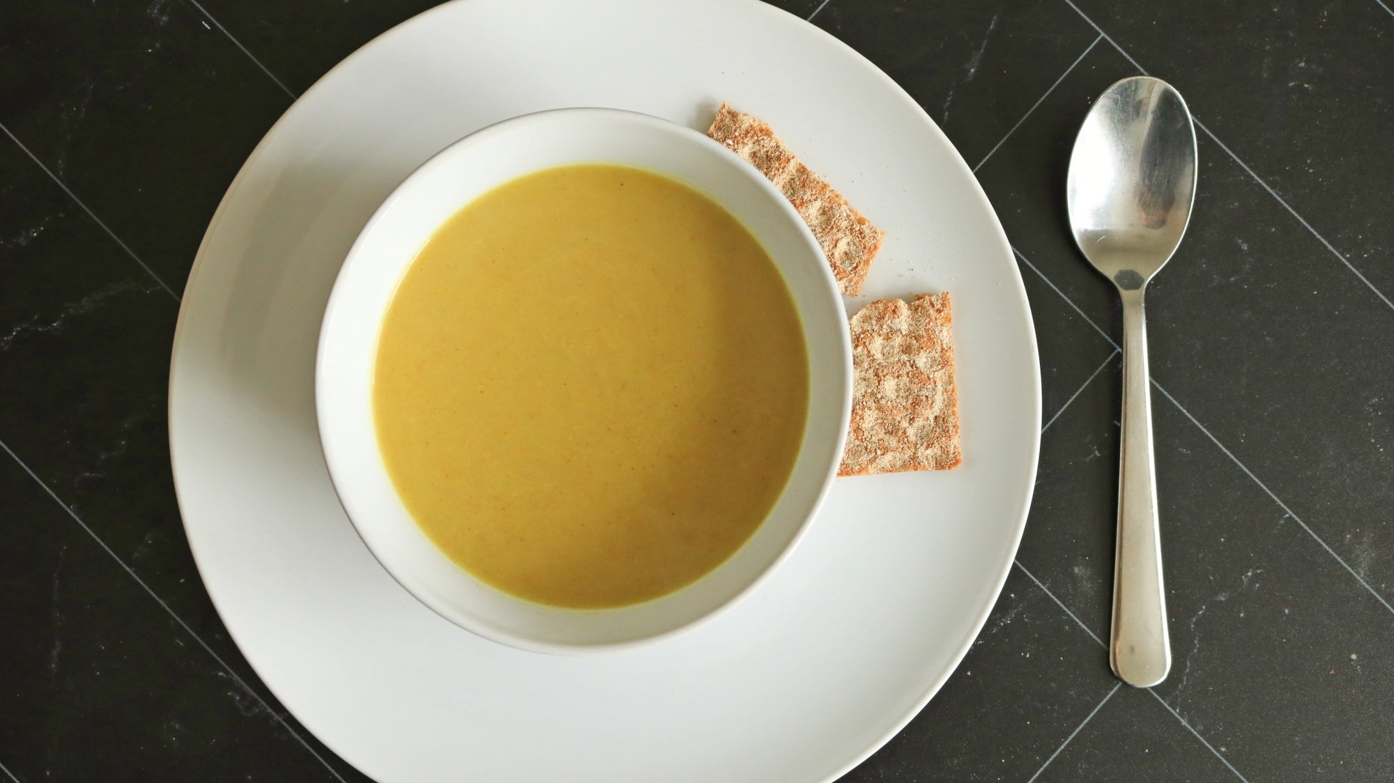 Uma tigela de sopa de couve -flor ao curry em uma mesa.